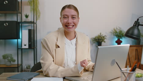 Mujer-De-Negocios-Trabajando-En-Una-Computadora-Portátil-Sonriendo-Amablemente-A-La-Cámara,-Agitando-Las-Manos-Y-Haciendo-Gestos-De-Saludo-En-La-Oficina