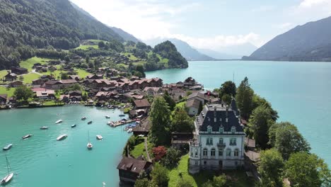 drone view of the village of iseltwald, nestled in a picturesque bay with a harbor and boats, set against the stunning landscape of lake brienz in switzerland