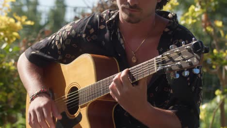 close-up of an italian man strumming his acoustic guitar in the serene garden of anacapri, capri island