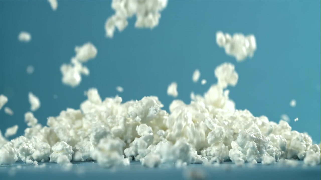 Ricotta fresca che cade su una superficie blu al rallentatore