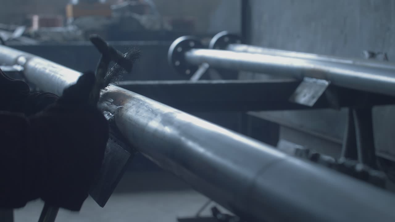 Nærbillede af en arbejder, der svejser metalrør på en fabrik