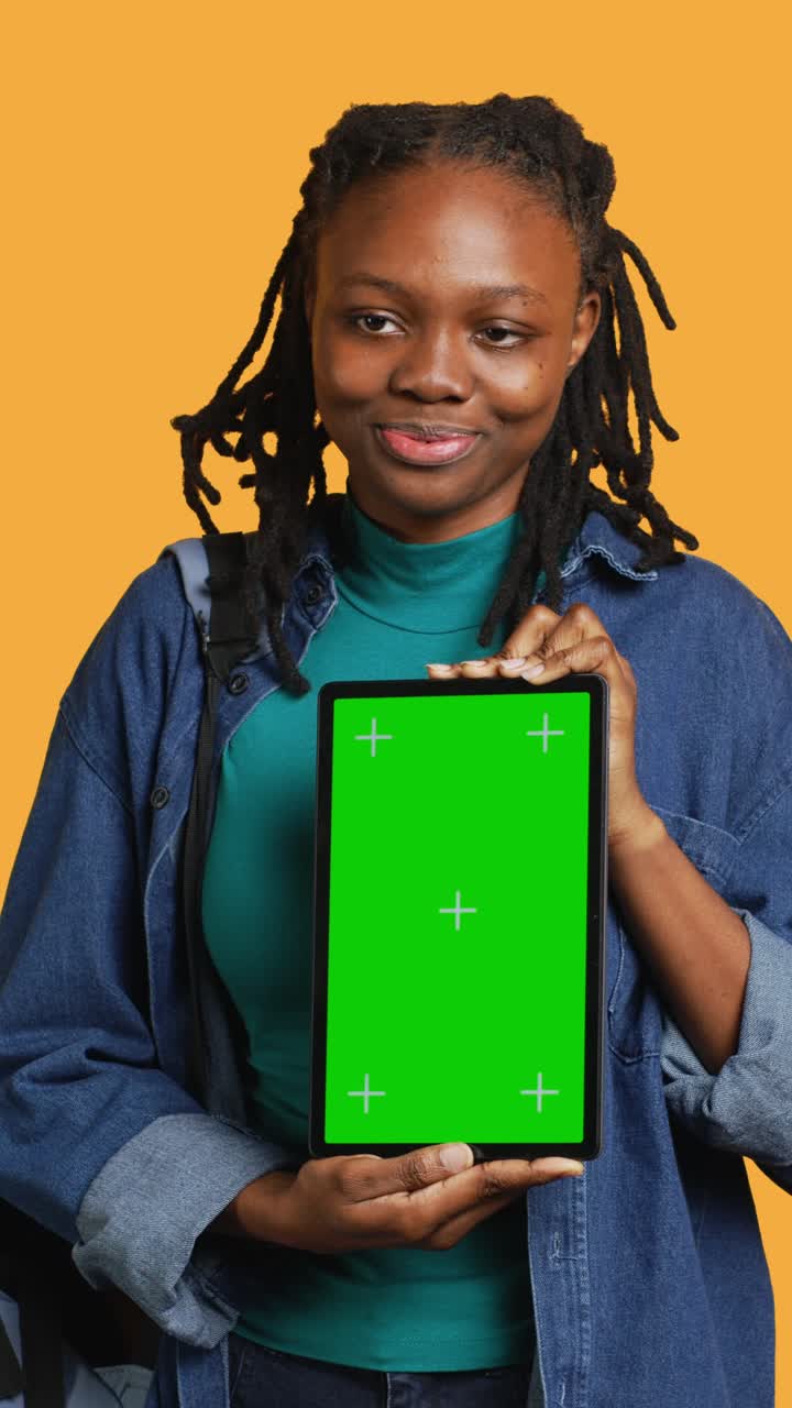 Giovane donna afroamericana che tiene in mano un tablet con green screen