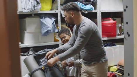 padre e hijo multiétnicos empacando una mochila para acampar