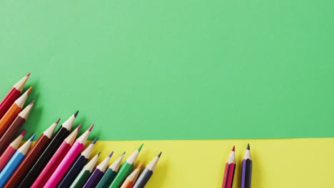 Video-of-composition-with-colorful-crayons-on-green-and-yellow-background-with-copy-space