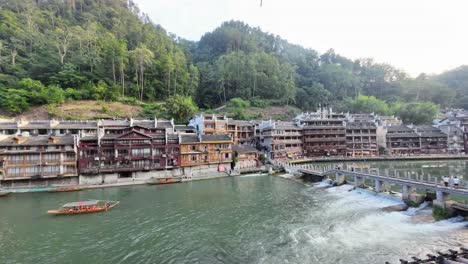 time lapse of wooden boats moving along the tuojiang river in fenghuang old town, hunan, with stilt houses and traditional chinese architecture by the water