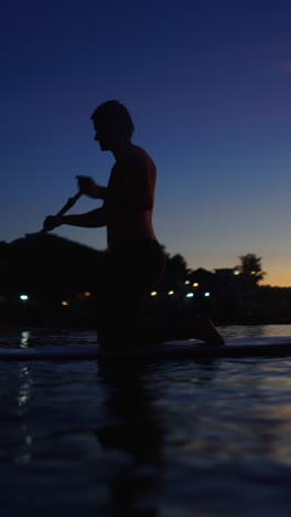 silhouette of a person paddleboarding at sunset
