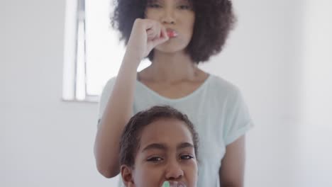 Happy-african-american-mother-and-daughter-brushing-teeth-in-bathroom,-slow-motion