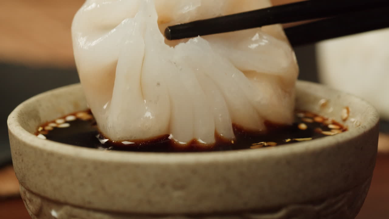 Dipping a Steamed Dumpling into Soy Sauce with Chopsticks