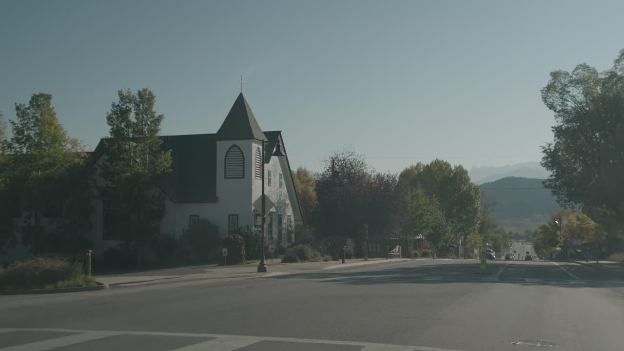 A church along a road with trees in a small town