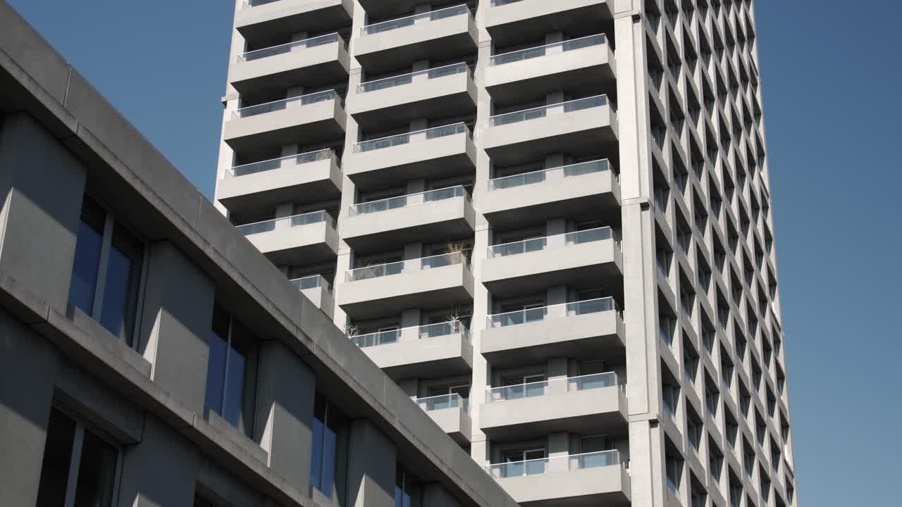 Urban scene with modern high-rise and adjacent mid-rise apartment under clear blue sky
