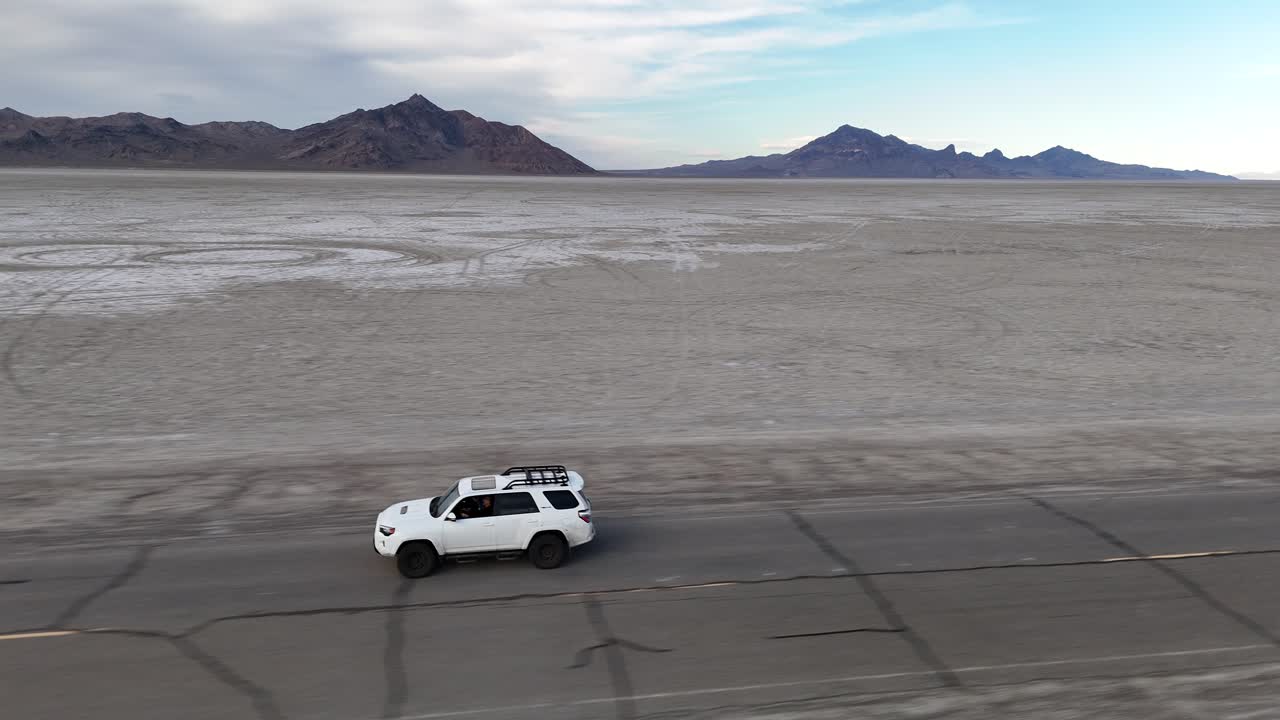 Tracking Drone Shot of White SUV Vehicle on Asphalt Road by Bonneville Salt Flats, Utah USA