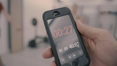 closeup of a countdown on a smartphone with a man and a woman jumping ropes in the back in slow motion