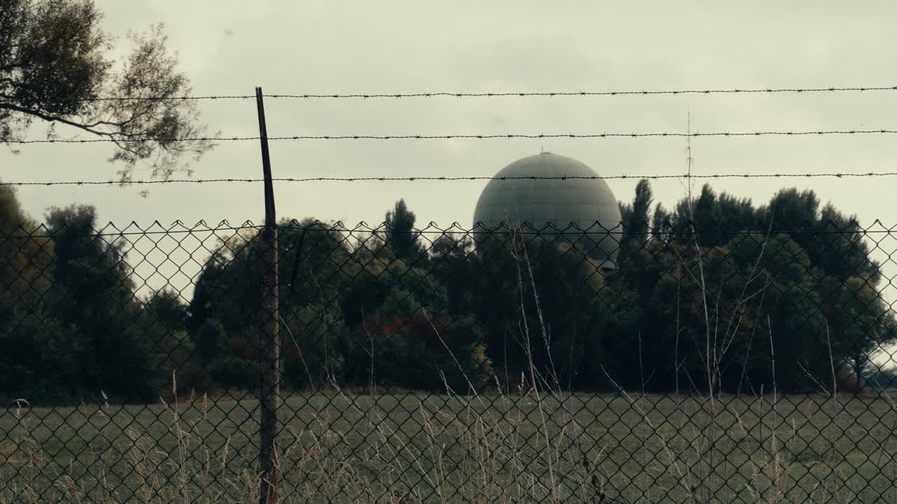 Large Radar Dome Behind Barbed Wire Fence and Trees