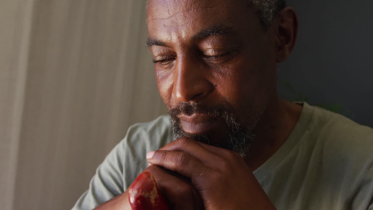 Close-up de homem afro-americano segurando uma bengala em casa.