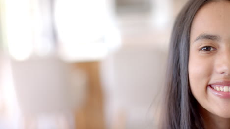 biracial young girl smiling, light-filled room behind, at home, with copy space