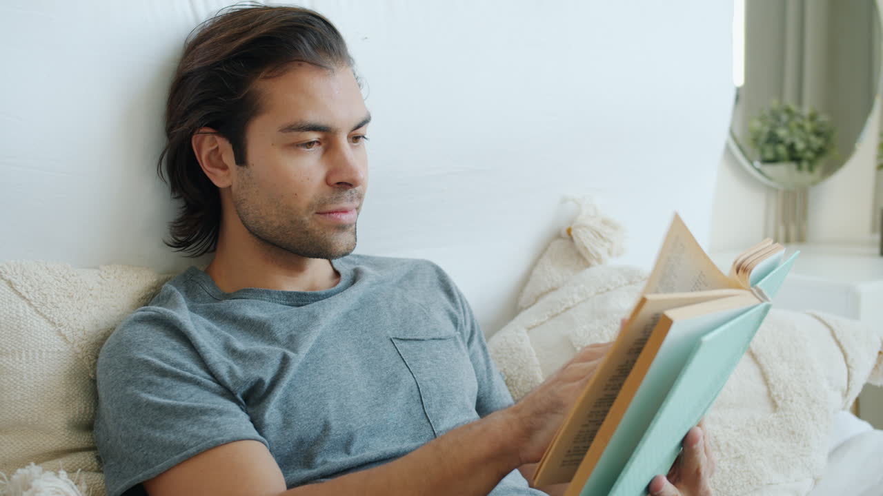 Mann liest ein Buch im Bett