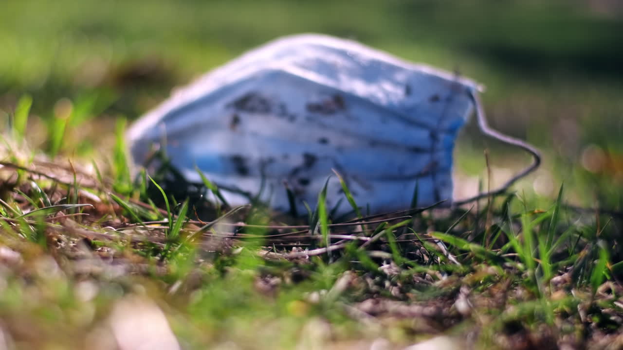 Dirty medical mask is lying on the grass. Pollution idea