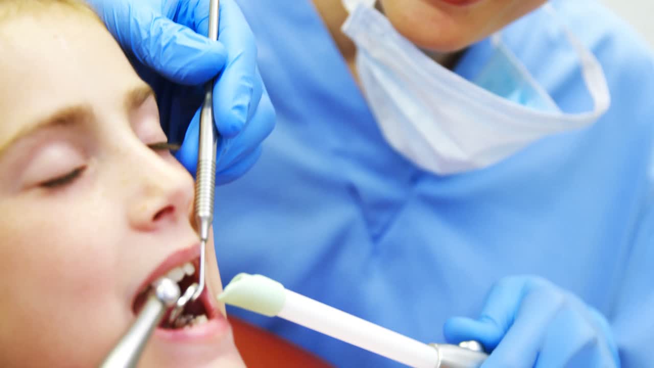 치과의사 들 이 도구 를 가지고 어린 환자 를 검사 하고 있다