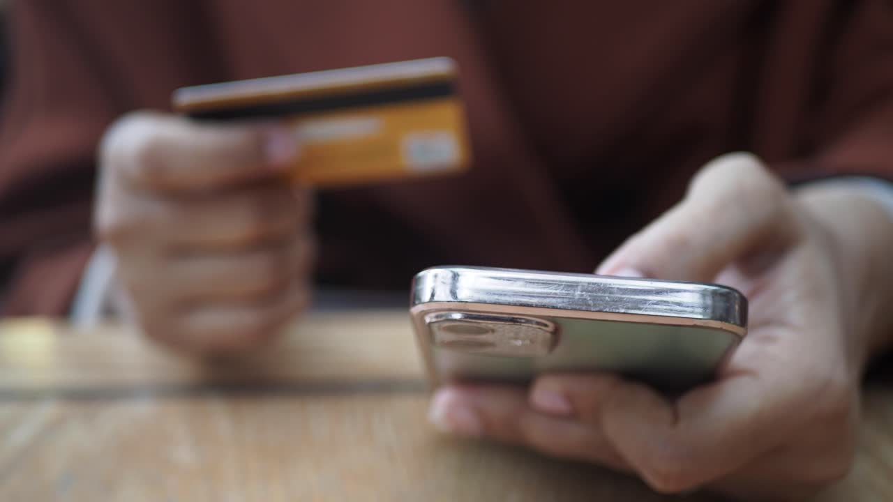 una mujer usa su teléfono y tarjeta de crédito para hacer una compra en línea.