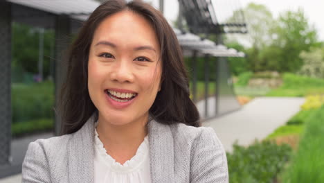 Portrait-Of-Smiling-Businesswoman-Standing-Outside-Modern-Office-Building