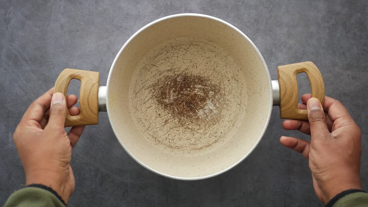 Close-up of Hands Holding Used Cooking Pot