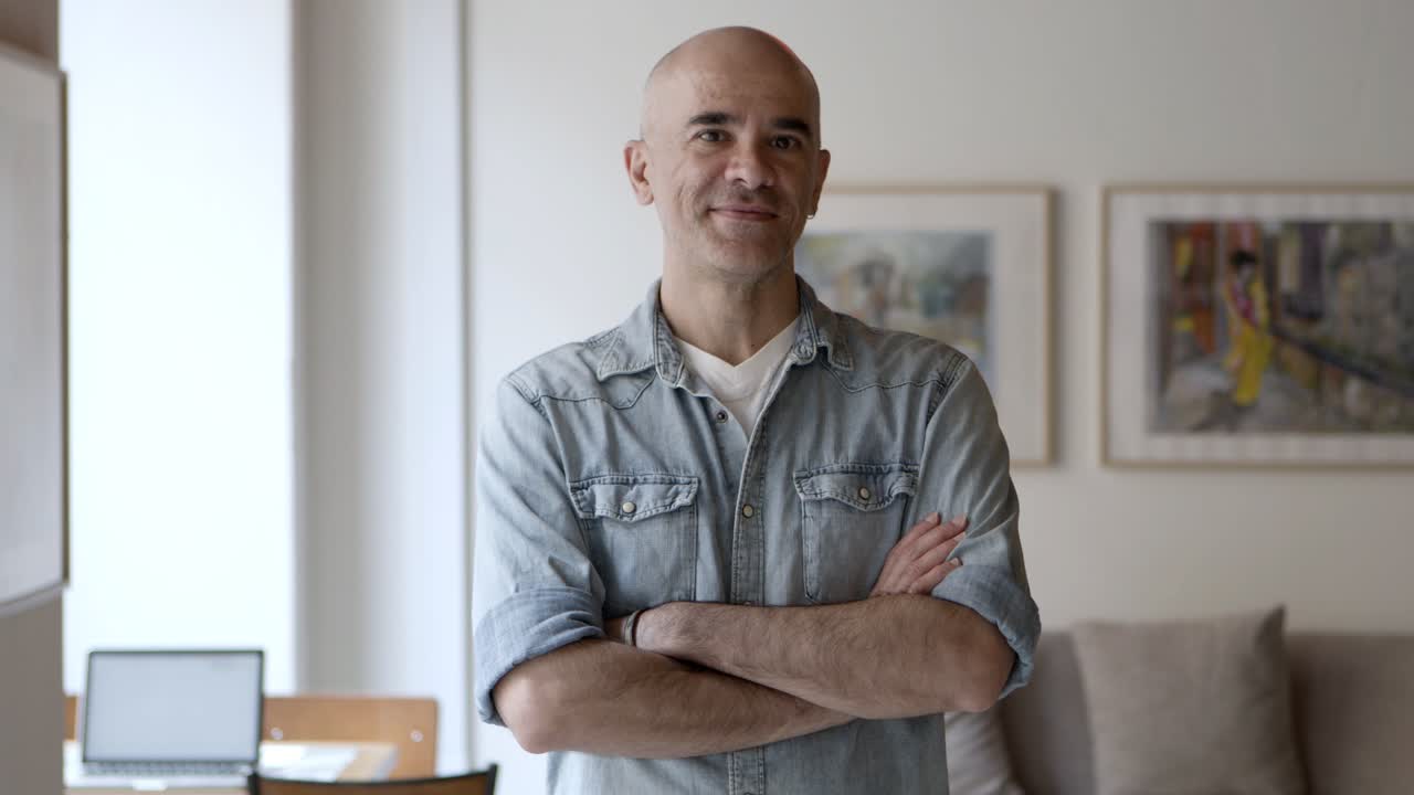 hombre calvo guapo y serio posando con los brazos cruzados