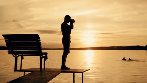 photographer taking picture of landscape during sunset. silhouette of people swimming in the river at sunset