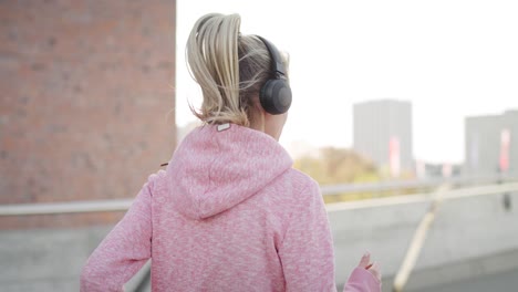 mujer deportiva corriendo y escuchando música en la ciudad