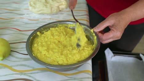 hands of woman mixing cheese with eggs for pies filling