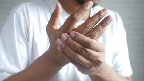 primer plano de una persona sosteniendo sus manos, lo que indica un posible dolor en la mano o en el dedo.