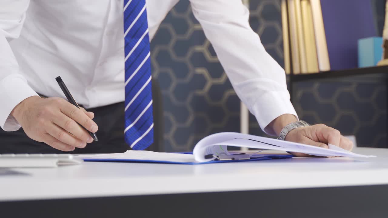 Close-up of a businessman's hands signing a contract in a modern workplace.