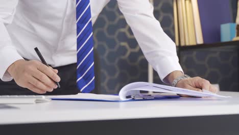 Close-up of a businessman&#039;s hands signing a contract in a modern workplace.