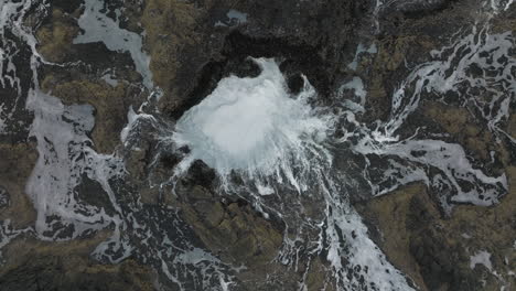 waves and water sucked into rocks at thor's well, oregon coast, spread and wash across this dangerous zone, drone top down