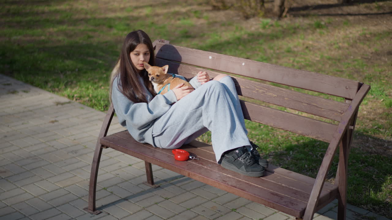 화창한 날, 평온한 여성이 야외 공원에서 즐거운 시간을 보내고 있어요. 차분한 여성이 털북숭이 친구 옆에서 행복하게 휴식을 취하고 있고, 평화로운 여성이 충실한 반려견과 함께 공원에서 편안하게 휴식을 취하고 있네요.