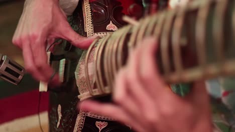 4k close up of mans hands playing an indian instrument called a sitar