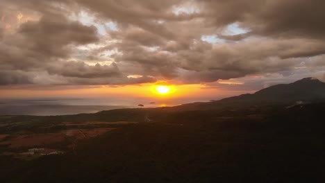 golden sunset behind dark clouds over biliran island in philippines. silhouette of mountains range and sea in background. drone wide shot.