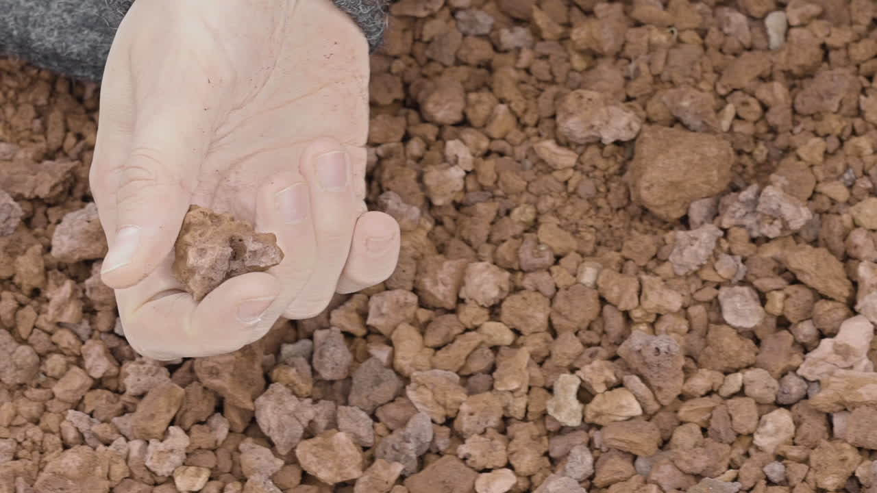 Close-up of a woman's hand sensually playing with volcanic gravel