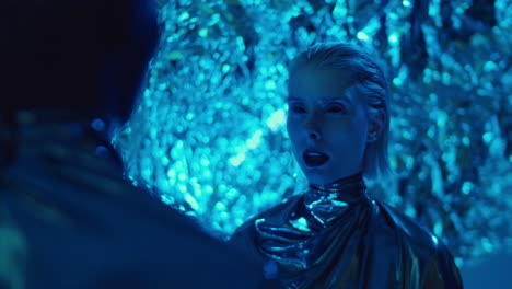 alien woman speaking with man in room with neon light