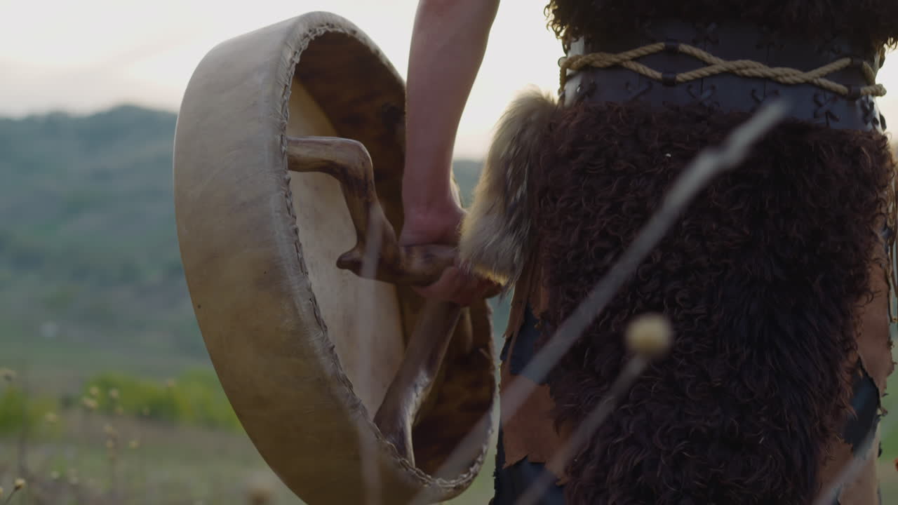 el chamán camina con un tambor ritual a lo largo de un valle montañoso