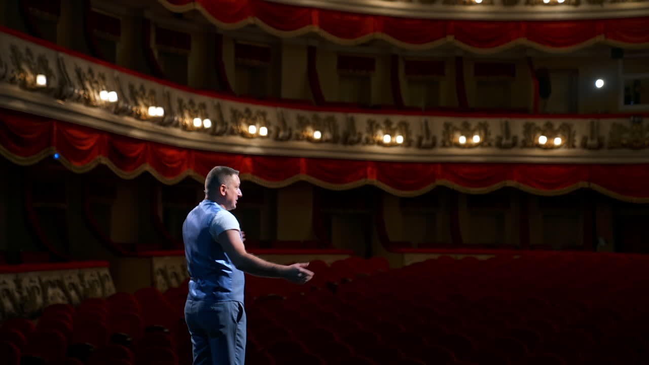 Rehearsal before the performance. Actor man is talking to the empty auditorium during pandemic in the world. Speaker talking in the theater with no people.