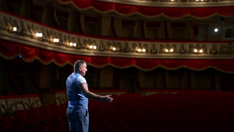 rehearsal before the performance. actor man is talking to the empty auditorium during pandemic in the world. speaker talking in the theater with no people.