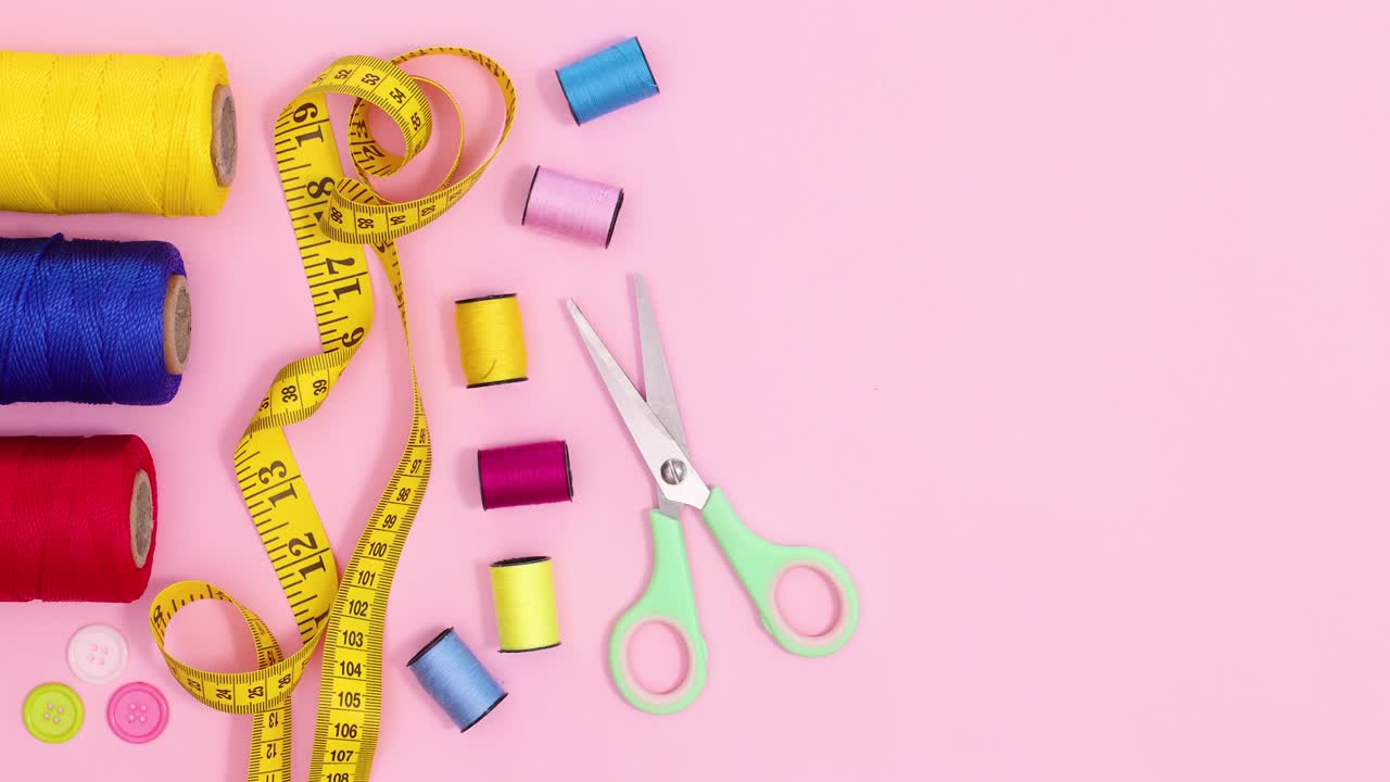 Creative craft sewing items appear on pastel pink background with copy space. Stop motion flat lay