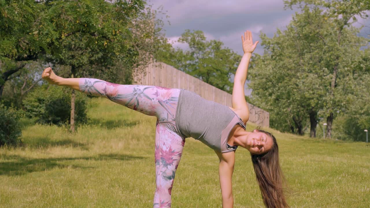 mujer caucásica tiene pose de yoga lateral en la naturaleza, inclinación de cámara lenta