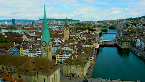4k drone video of the historic grossmünster church and opera house on the banks of the limmat river in downtown zurich, switzerland