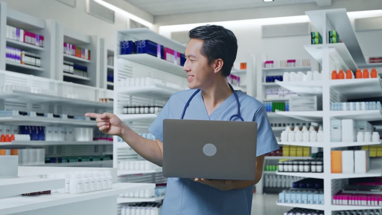 스테토스코프를 들고 노트북을 들고, 을 가리키며 약국에서 웃는 아시아 남성 의사