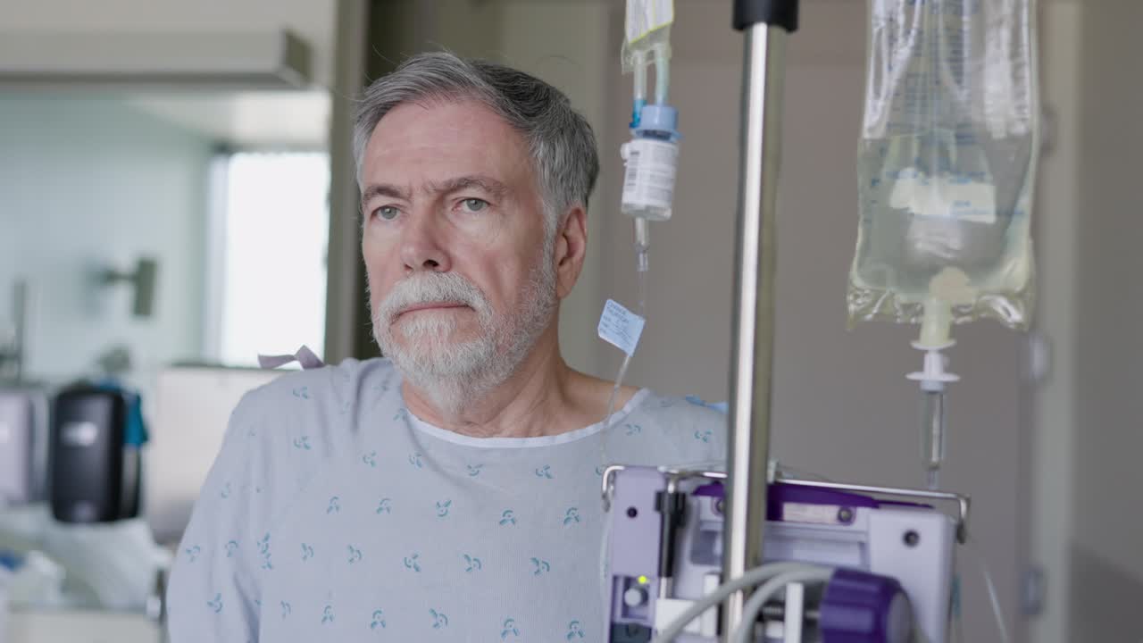 A hospitalized senior adult hooked up to an IV solution being delivered by an infusion pump on a stand that can be wheeled around.