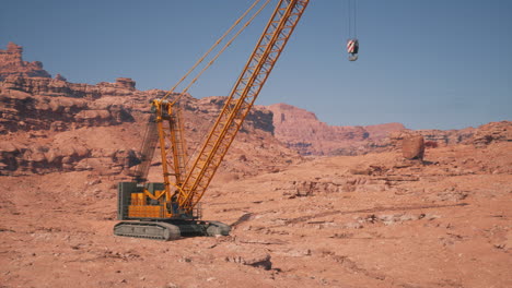 a yellow construction crane in a desert canyon