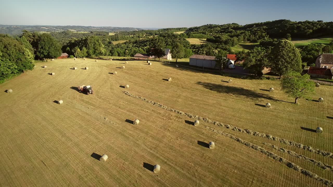 взгляд с воздуха на трактор, собирающий соломенные балы.