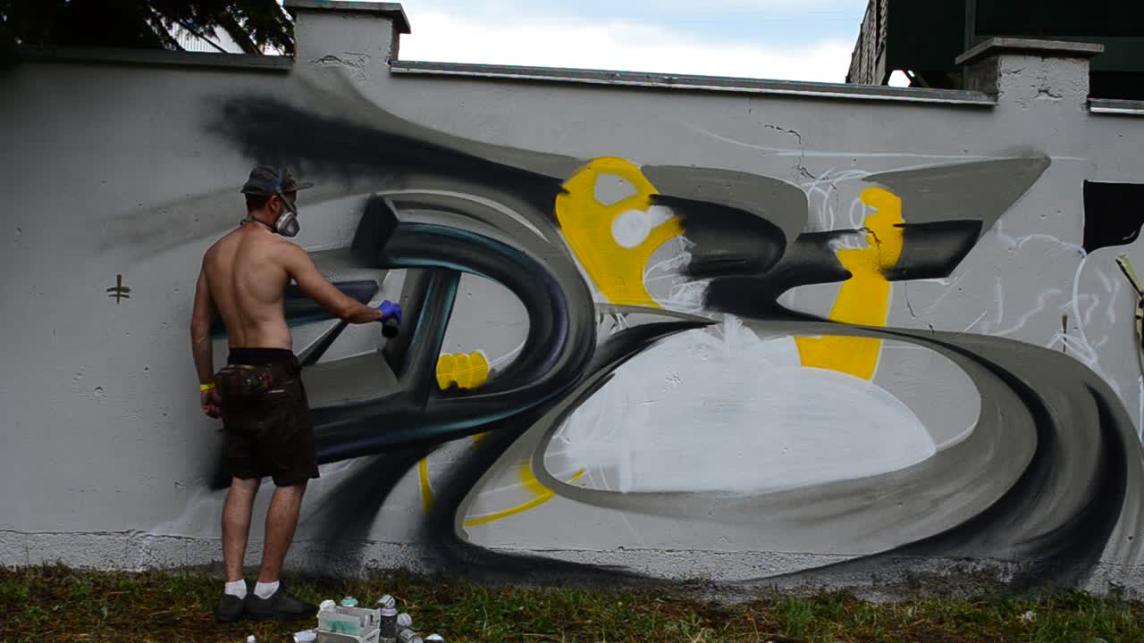 Sanatçı bir çit üzerine grafiti çiziyor.