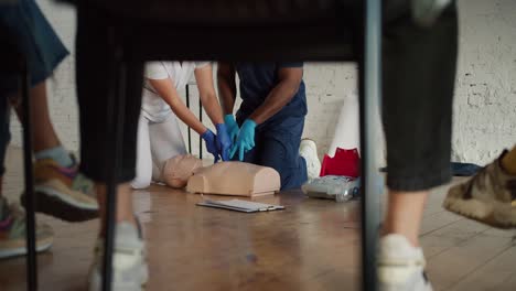 Bottom-view:-A-Black-male-doctor-in-a-blue-uniform,-together-with-his-assistant,-a-female-nurse-in-a-white-uniform,-conducts-artificial-respiration-training